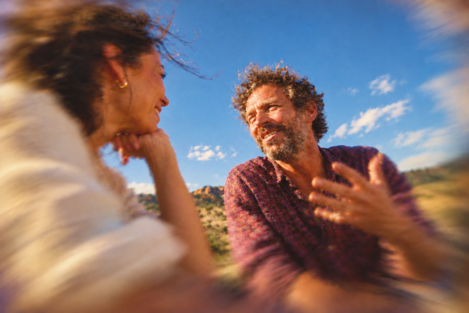 Two adults face each other in conversation outdoors.